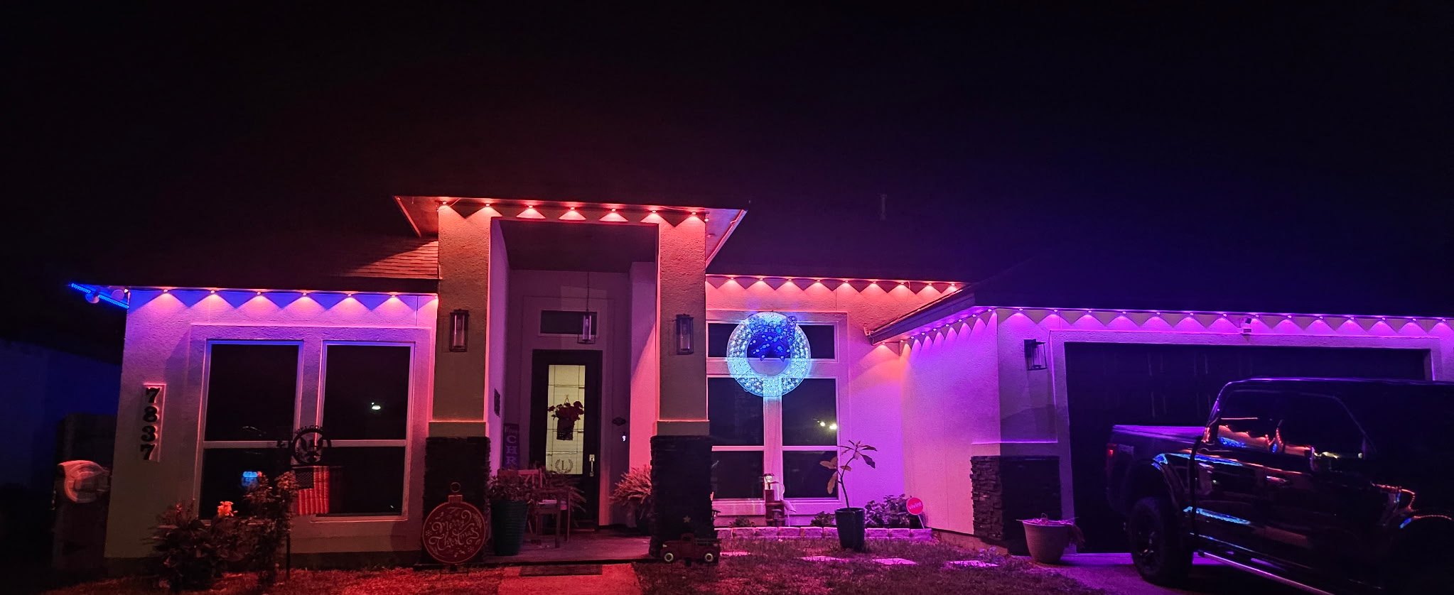 Dramatic red and blue scalloped Entry Series roofline downlighting on a modern home by H&L